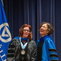 Provost Mili laughs next to woman on stage